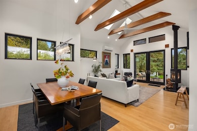 The dining and living room with vaulted ceiling, wood cross-beams, skylights and a ceiling fan.