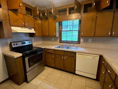 Kitchen featuring under cabinet range hood, stainless steel electric range oven, dishwasher, a sink, and tile countertops