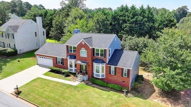 Colonial-style house with brick siding, concrete driveway, roof with shingles, an attached garage, and a front lawn