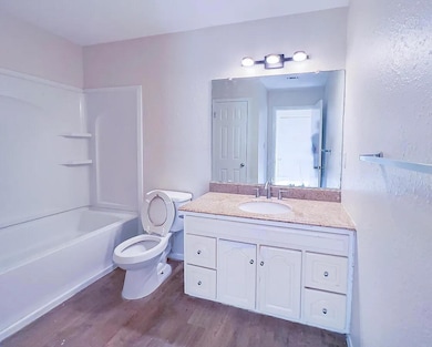 Bathroom with dark wood-style floors, vanity, and shower / washtub combination