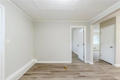 Empty room with ornamental molding, a textured ceiling, and light wood-type flooring