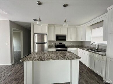 Kitchen with appliances with stainless steel finishes, a sink, dark wood-type flooring, and a center island