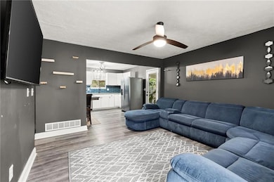 Living area featuring light wood-style flooring, a ceiling fan, a textured ceiling, and a chandelier