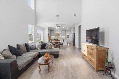 Living room with light wood-style floors, a high ceiling, and a ceiling fan