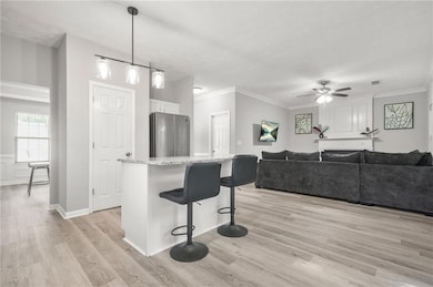 Kitchen with freestanding refrigerator, a breakfast bar area, white cabinets, light wood-style floors, and open floor plan