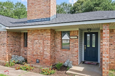 Property entrance with a chimney, a shingled roof, and brick siding