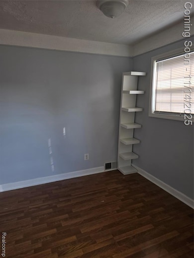 Empty room featuring dark wood finished floors and a textured ceiling