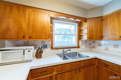 Kitchen featuring light countertops, brown cabinets, white microwave, and backsplash