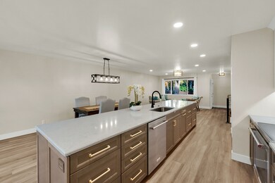 Kitchen with recessed lighting, light wood-style floors, decorative light fixtures, an island with sink, and stainless steel appliances