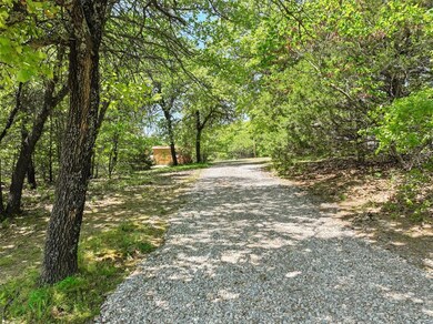 Tree lined driveway leading to the home that is tu