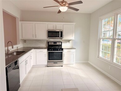 Kitchen with stainless steel appliances, white cabinets, and backsplash
