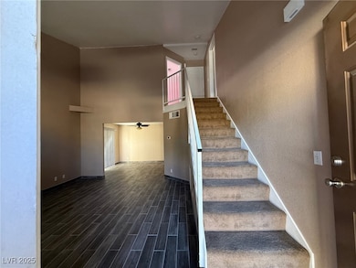 Stairway featuring wood finish floors, a ceiling fan, and a high ceiling
