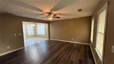 Empty room featuring a chandelier, a ceiling fan, dark wood-style flooring, and a textured ceiling