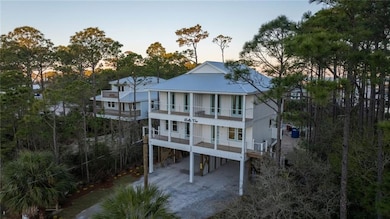 Rear view of house with a carport, a patio, a balcony, view of scattered trees, and driveway