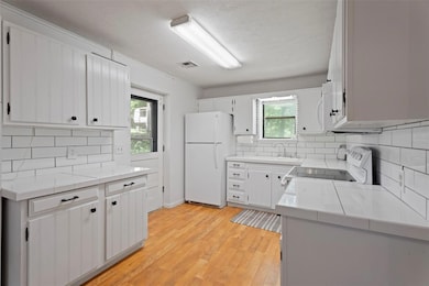 Kitchen with white appliances, healthy amount of natural light, decorative backsplash, and a textured ceiling