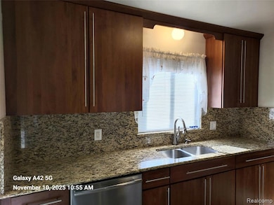 Kitchen featuring light stone counters, dark brown cabinetry, dishwasher, and tasteful backsplash