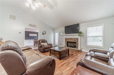Living room with ceiling fan, light wood-type flooring, a fireplace, and high vaulted ceiling
