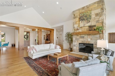 Living area featuring high vaulted ceiling, light wood-style floors, a stone fireplace, and recessed lighting