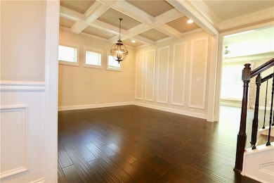 Spare room featuring dark hardwood / wood-style floors, beam ceiling, a healthy amount of sunlight, and coffered ceiling