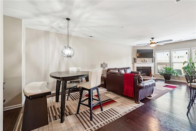 Dining space with hardwood / wood-style floors, ceiling fan, a fireplace, and baseboards