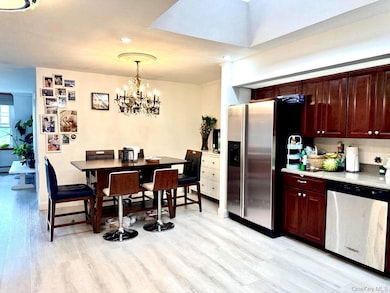 Kitchen featuring appliances with stainless steel finishes, light wood finished floors, decorative light fixtures, a chandelier, and decorative backsplash