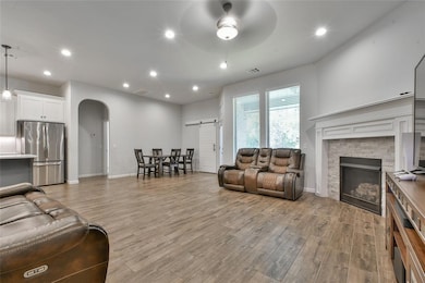 Living room featuring a barn door, arched walkways, recessed lighting, light wood-style floors, and a fireplace