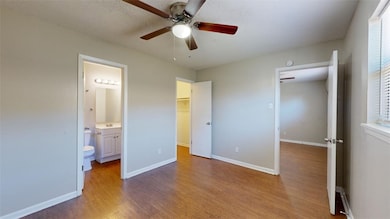 Unfurnished bedroom with dark wood-style flooring, a walk in closet, a ceiling fan, and connected bathroom
