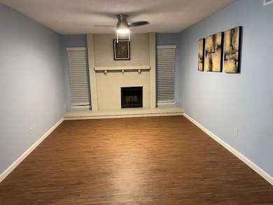 Unfurnished living room with a textured ceiling, dark wood-type flooring, a fireplace, and a ceiling fan