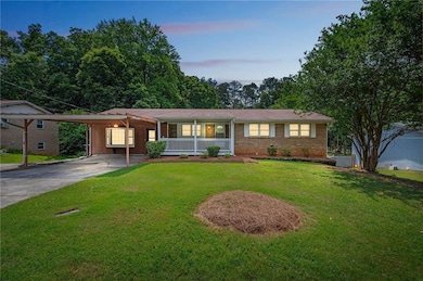 Ranch-style home featuring covered porch, driveway, an attached carport, brick siding, and a lawn