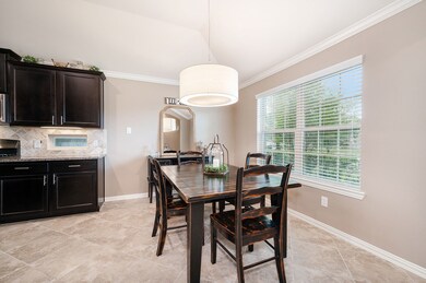 Dining area just off the kitchen with crown molding and a modern light fixture.