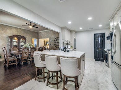 Kitchen with a breakfast bar, light stone countertops, stainless steel appliances, a peninsula, and light marble finish floors