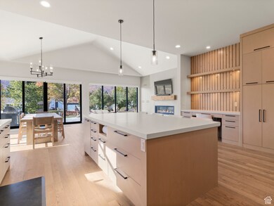 Kitchen with modern cabinets, pendant lighting, open shelves, lofted ceiling, and light wood-style flooring