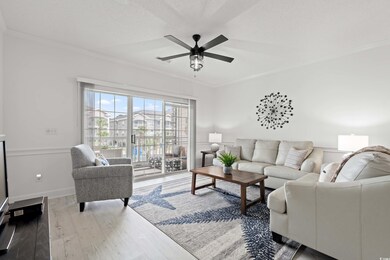 Living area with wood finished floors, ornamental molding, and ceiling fan
