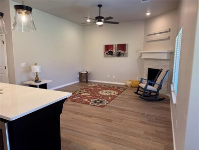 Living area featuring light wood-style floors, a stone fireplace, ceiling fan, and recessed lighting