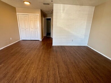 Unfurnished living room featuring a textured ceiling, a closet, and dark wood finished floors