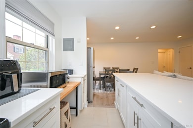 Kitchen with white cabinetry, recessed lighting, stainless steel appliances, light tile patterned flooring, and electric panel