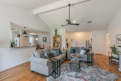 Living room featuring beamed ceiling, high vaulted ceiling, ceiling fan, and light wood-type flooring