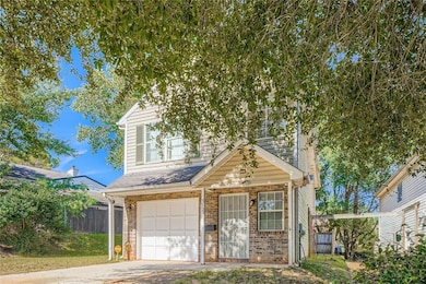 Traditional-style house featuring an attached garage, brick siding, concrete driveway, and a shingled roof