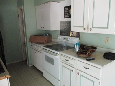Kitchen with white electric stove, white cabinets,