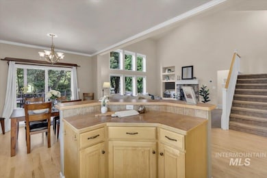 Kitchen with a chandelier, light wood-type flooring, open floor plan, light brown cabinetry, and crown molding