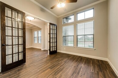 Empty room with baseboards, crown molding, arched walkways, and dark wood-style flooring