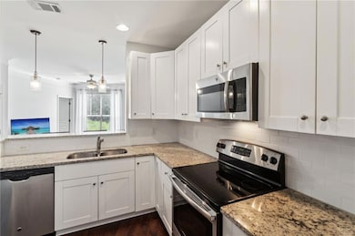 Kitchen featuring appliances with stainless steel finishes, a sink, white cabinets, decorative backsplash, and ornamental molding