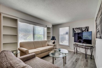 Living room with wood finished floors, a textured ceiling, healthy amount of natural light, and baseboards
