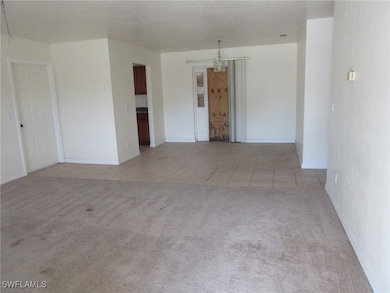 Unfurnished room featuring light carpet, a chandel