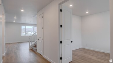 Hallway featuring light wood-type flooring, recessed lighting, and stairs