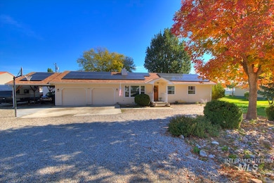Ranch-style house with a garage, driveway, a chimney, and roof mounted solar panels