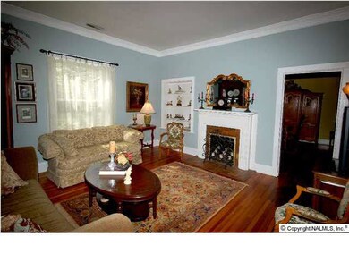 As you enter the home, to the left of the foyer is a roomy formal living room with high ceilings, crown molding, pine floors, and fireplace. Door at the right leads to the formal dining room.