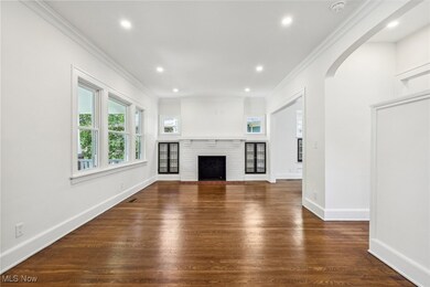 Living room with crown molding, dark hardwood flooring, and a fireplace