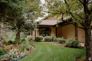 View of front facade with a front yard, stucco siding, and roof with shingles