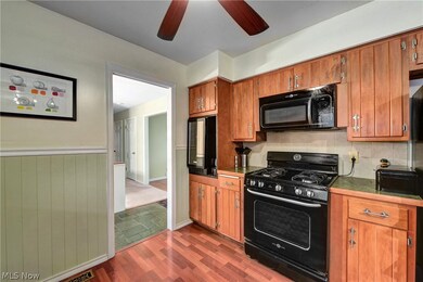 Kitchen with dark tile flooring, backsplash, ceiling fan, and black appliances